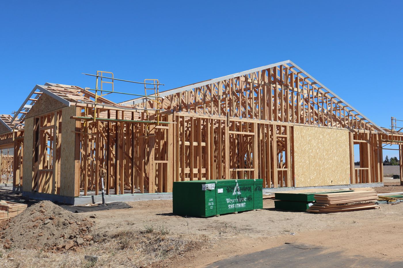 Framed custom home under construction against a clear sky